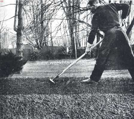 Gras onder boomen. De bovengrond wordt met een grove ijzeren hark flink, diep losgeharkt