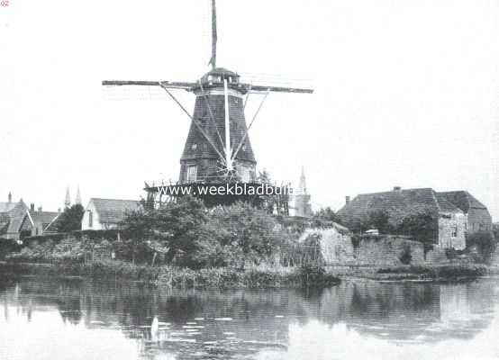 Utrecht, 1915, Montfoort, Montfoort. Gezicht op de stadsgracht en den molen. Rechts overblijfselen van de oude wallen, gedeeltelijk als buitenmuur van arbeiderswoningen gebruikt