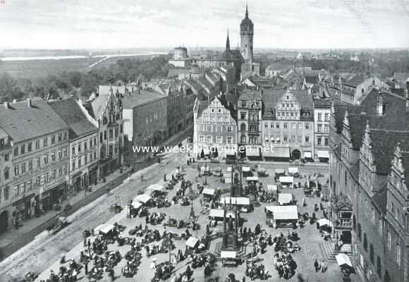 Wittenberg. Panorama van het Westelijk deel der stad. Op den voorgrond de Markt met Stadhuis (rechts) en standbeelden van Luther en Melanchton. De toren op den achtergrond is die van de Slotkerk. Links daarvan de overblijfselen van het keurvorstelijk slot, thans kazerne. Links op den achtergrond de Elbe