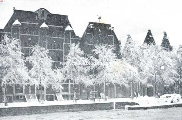 Noord-Holland, 1918, Amsterdam, Een herinnering aan den sneeuwval in de afgeloopen week. Boomen in hun sprookjesachtige sneeuwkleed voor oude pakhuizen aan de Oude Schans te Amsterdam