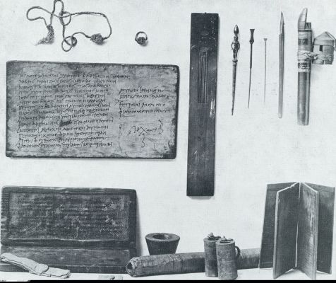 Antiek schrijfgereedschap. Bovenaan v.l.n.r. zegelsteen, zegelring, schrijverspalet met holle pennen en kleurvakjes, 3 metalen stili, holle pen met bijbehoorende inktpot; 2e rij: houten tafel met schrijfoefening; 3e rij v.l.n.r. dubbele wastafel met daarvoor verzegelde papyrusbrieven, papyrusrol, enkele en dubbele inktpot, notieboekje van wastafeltje (Nat. Museum, Berlijn)