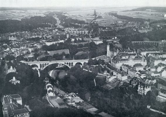 LUXEMBURG, DE HOOFDSTAD FAN HET GELIJKNAMIGE GROOTHERTOGDOM LUXEMBURG LIGT IN HET ZUIDEN, MIDDEN IN DAT DEEL DES LANDS HETWELK MEN GOEDLAND NOEMT. DE MACHTIGE ADOLFSBRUG OP DEN VOORGROND VERBINDT DE MODERNE VOORSTAD MET DE OUDE BINNENSTAD. (LUCHTFOTO)