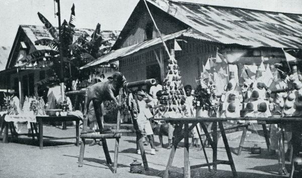 Indonesi, 1933, Onbekend, LANGE RIJEN FEESTTAFELS. OP DE MIDDELSTE STELLAGE GEBRADEN SPEENVARKEN