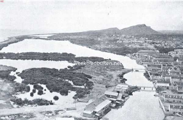 Curaao, 1934, Willemstad, Curaao voorheen en thans. Het Rifwater ten z. van Otrabanda (de overzijde), het gedeelte van Willemstad ten w. van de haven. Aan de linkerzijde koraalriffen, die langs een groot deel van de zuidkust van Curaao te vinden zijn